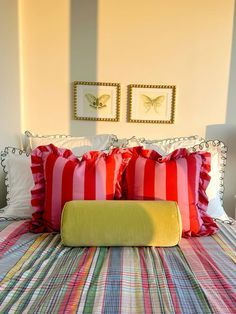 a bed with red and white pillows on top of it next to two framed pictures