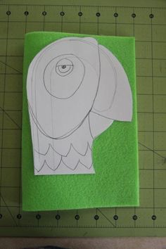 a paper cut out of an elephant on top of a green cutting mat with scissors next to it