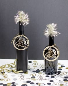 two wine bottles decorated with gold and silver confetti are sitting on a table