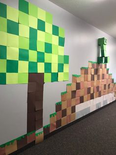 an office cubicle decorated with green and brown paper squares on the wall, along with a tree