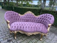 a purple couch sitting on top of a brick road