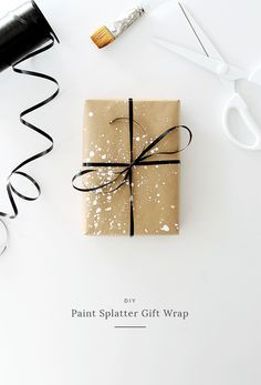 a gift wrapped in brown paper and tied with black ribbon on top of a white table