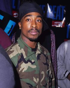 a man in camo shirt and hat standing next to other people