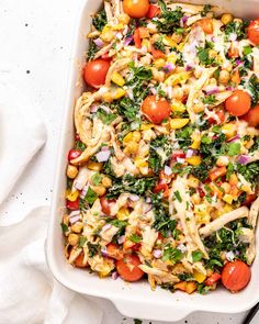 a casserole dish filled with pasta, vegetables and dressing on a white surface