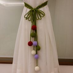 a white dress with crocheted balls attached to it