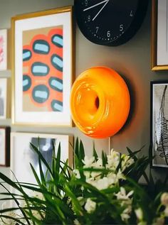 an orange donut hanging from the side of a wall next to pictures and flowers