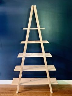 a wooden christmas tree sitting on top of a hard wood floor next to a blue wall