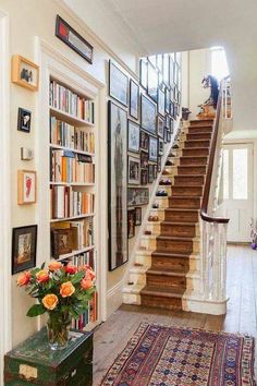 the stairs in this house are lined with bookshelves and vases filled with flowers