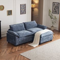 a blue couch sitting on top of a hard wood floor next to a white rug