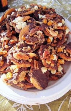 a white plate topped with lots of nuts and raisins next to a bottle of beer