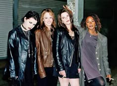 four women in leather jackets posing for a photo together with one holding her hand up