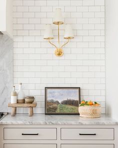 a white kitchen with marble counter tops and gold accents on the wall above it is a framed painting