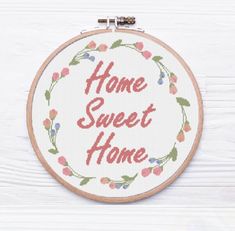 a cross stitch hoop with the words home sweet home in red and green on it