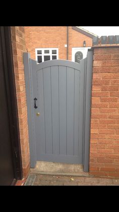 a grey gate is open on the side of a brick building