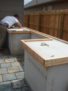 a man working on an outdoor kitchen in the back yard with bricks and pavers