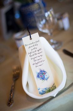 an empty dish with a note attached to it sitting on a table next to silverware