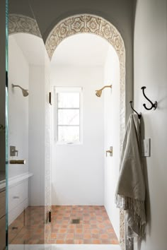 a bathroom with an arched doorway and tiled flooring, along with a window in the corner