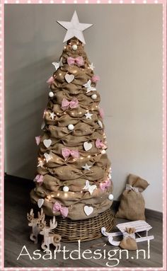 a christmas tree made out of burlocks and pink bows is shown in front of a basket