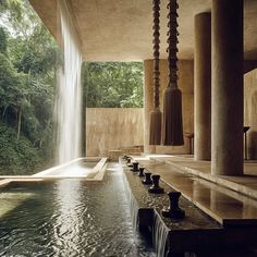 an indoor swimming pool with water flowing from it's sides and several lamps hanging above