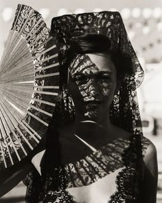 a woman wearing an elaborate head piece and holding a fan