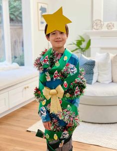 a young boy wearing a christmas tree costume with a star on his head, standing in a living room