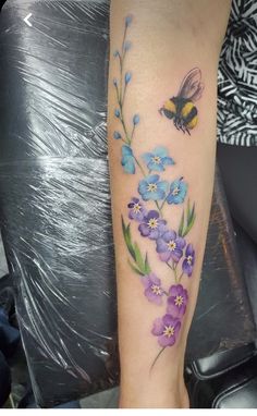 a woman's leg with flowers and a bee on it