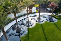 an aerial view of a circular garden with fountains and palm trees in the foreground