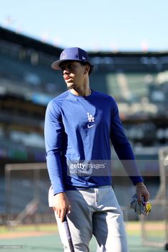 a baseball player is walking on the field with his bat in hand and ball mitt in