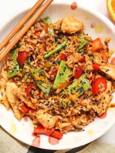 a white plate topped with rice and veggies next to chopsticks on a table