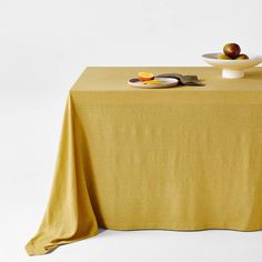 a table topped with an apple and plate of fruit on top of a yellow cloth