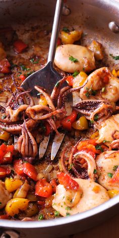 an octopus is being cooked in a skillet with tomatoes, peppers and other vegetables