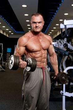 a man holding two dumbs in his hands and standing next to a barbell