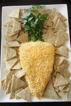 a white plate topped with crackers and cheese next to parsley on top of tortilla chips