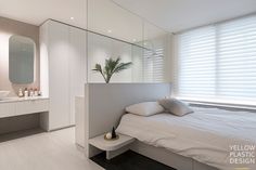 a white bed sitting next to a bathroom sink under a large mirror on the wall