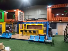 the stage is set up for an event with blue chairs and yellow containers on it