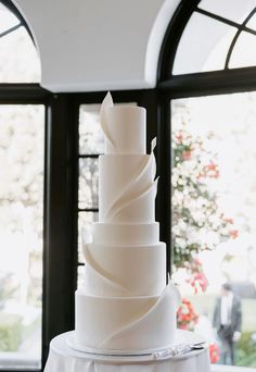 a white wedding cake sitting on top of a table in front of a large window