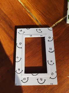 a small white frame sitting on top of a wooden floor next to a box with a smiley face drawn on it