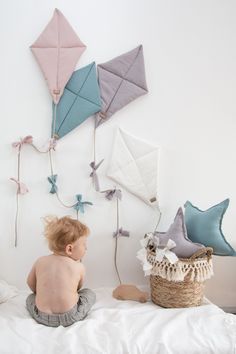 a baby sitting on a bed next to some kites