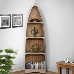 a wooden shelf with books and vases on it in a living room next to a potted plant