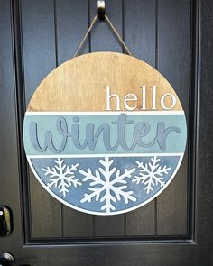 a wooden sign that says hello winter hanging on the front door with snowflakes