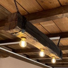 three light bulbs hanging from the ceiling in a room with wood planks and beams