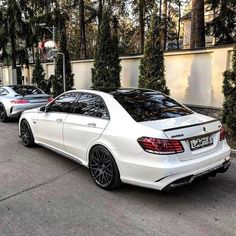 two white cars parked in front of some trees