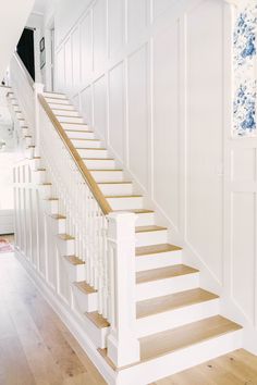 a white staircase with wooden handrails and wood flooring in a home's entryway