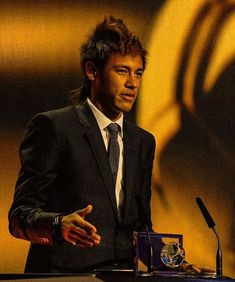 a man in a suit and tie standing at a podium with his hand on the table