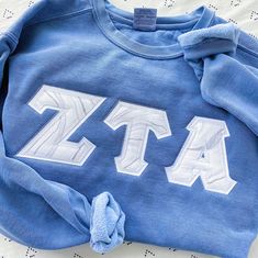 a blue sweatshirt with white letters that spell out the letter zta on it's chest