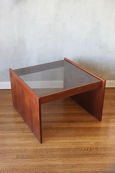 a coffee table sitting on top of a hard wood floor next to a white wall