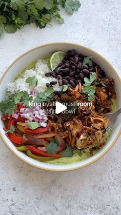 a bowl filled with meat, beans and veggies next to cilantro