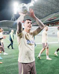 a man holding a soccer ball up in the air with other men standing around him