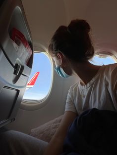 a woman sitting in an airplane looking out the window