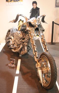 the motorcycle is made out of metal and has gold chains on it's front wheel